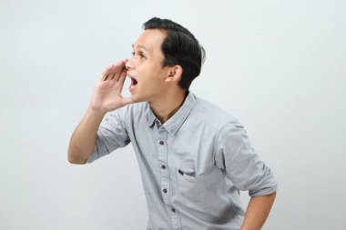 Genç Asyalı Endonezyalı bağırıyor ve izole edilmiş arka planda elleri ağızlarına dolanıyor.