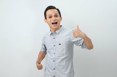 Neşeli, mutlu, kendinden emin Endonezyalı, parmak kaldıran, izole edilmiş bir geçmişi olan bir adam.