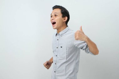 Neşeli, mutlu, kendinden emin Endonezyalı, parmak kaldıran, izole edilmiş bir geçmişi olan bir adam.