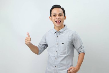 Neşeli, mutlu, kendinden emin Endonezyalı, parmak kaldıran, izole edilmiş bir geçmişi olan bir adam.