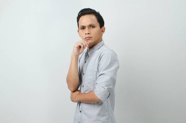 Ciddi bir suratı olan düşünceli Asyalı genç bir Endonezyalı soru hakkında düşünüyor, izole edilmiş arka planda kafa karıştırıcı bir fikir hakkında düşünceli.