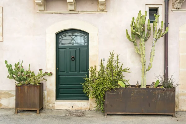 Facade of typical town house with green cactuses and old door in a Mediterranean city (Syracuse) on Sicily, Italy