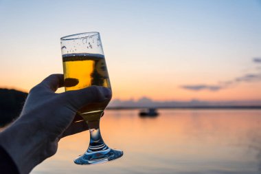 Having a fresh cold beer at the seashore during a beautiful sunset  clipart