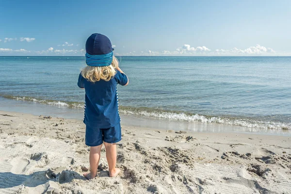 Νεαρό Παιδί Στέκεται Στην Παραλία Και Κοιτάζει Τον Όμορφο Γαλάζιο — Φωτογραφία Αρχείου