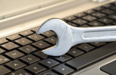 Bilgisayar bakımını sembolize eden klavyenin üzerine uzanan İngiliz anahtarı
