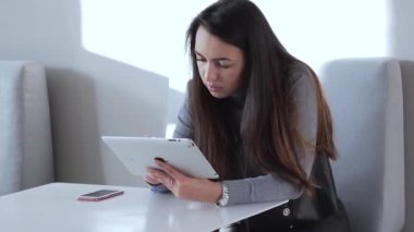 Ofisteki masada oturan ve ipad 'ini kullanan güzel bir kız. Orta boy. Yumuşak odak.