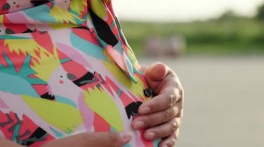 Hamile kız güzel bir elbise ve şapkayla yürüyor.