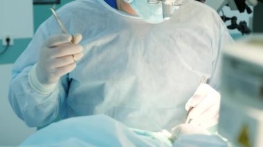 Cerrah ameliyat sırasında hastaya dikiş atar.