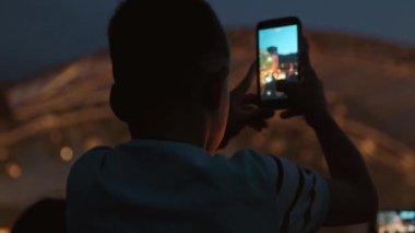 Çocukların silueti akıllı telefonlu canlı müzik konserinin fotoğrafını çekiyor ya da videosunu kaydediyor. Fotoğraf, eğlence ve teknoloji konsepti