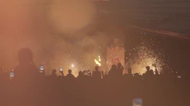 Renkli havai fişek gösterisinin arka planında duran bir grup insan. Gökyüzü güzelliğini izleyen mutlu siluetler