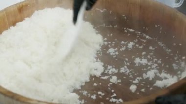 Aşçı sıcak pirinci ahşap bir kasede karıştırır.