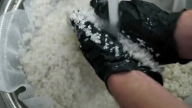 Aşçı pirinci musluktan gelen suyla yıkar. El yapımı, yıkama, karıştırma, geleneksel Asya pilavı