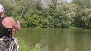 Gölde balık tutan engelli bir adam. Tekerlekli sandalye. Kamp yapmak. Yaz zamanı.