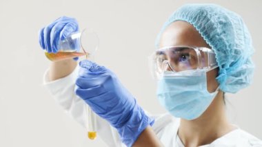 Kimyasal laboratuvar sahnesi: cam tüpte motor yağı veya bal gözlemleyen çekici genç doktora öğrencisi.