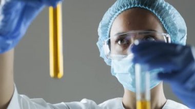 Kimyasal laboratuvar sahnesi: cam tüpte motor yağı veya bal gözlemleyen çekici genç doktora öğrencisi.
