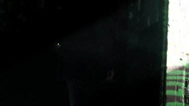 Karanlık bir koridorda elinde gaz lambasıyla yürüyen bir adam.