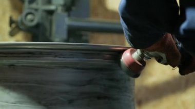 Master body repair man is working on preparing the surface of the aluminum wheel of the car for subsequent painting in the workshop, cleaning and leveling the wheel