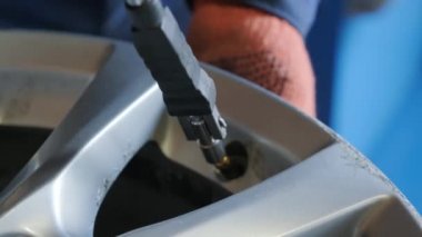 Close-up of male hands installing new nipple on the wheel disk of a car