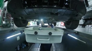 Mechanic in the pit checks bottom of car