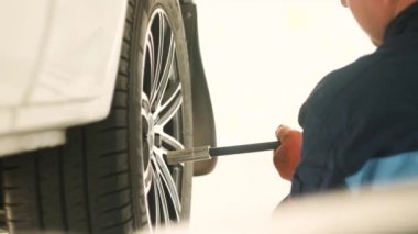 Tamir istasyonunda kaldırılan otomobilin vidaları vidalanmış veya sökülmüş araba tamircisi