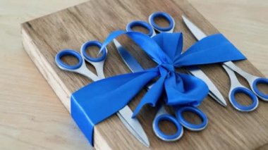 Scissors on a wooden board wrapped in blue satin ribbon
