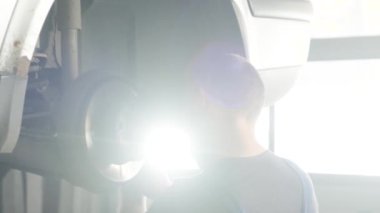 Tamir istasyonunda kaldırılan otomobilin tekerlek fren ayakkabılarını değiştiren araba tamircisi