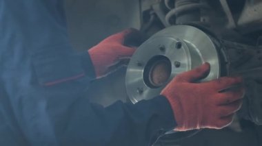 Tamir istasyonunda kaldırılan otomobilin tekerlek fren ayakkabılarını değiştiren araba tamircisi