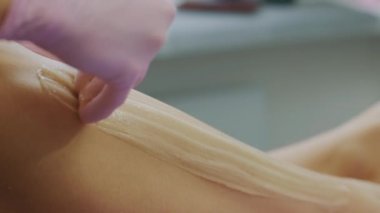 Ballı ya da şekerli makarnadan kadın bacakları tüy döküyor. Şekerleme ve saç kesimi. Güzellik konsepti. Şekerleme. Epilasyon süreci. Bacaklar.