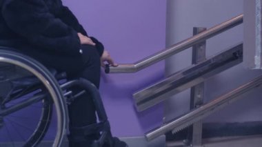 Tekerlekli sandalyedeki engelli kadın mekanik asansörle merdivenlerden çıkıyor..