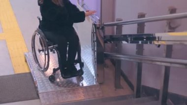 Tekerlekli sandalyedeki engelli kadın mekanik asansörle merdivenlerden çıkıyor..