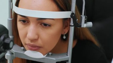 Göz doktorunda doktor ve güzel bir kadın göz testi makinesine bakıyor. Göz doktoruyum. Tıbbi yardım. Profesyonel göz doktoru muayene ediyor.