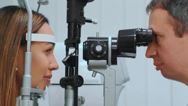 光学或眼科医生用折射计测量的眼睛 眼科医生在临床医生测量年轻妇女眼压时测量年轻妇女眼压 — 图库视频影像