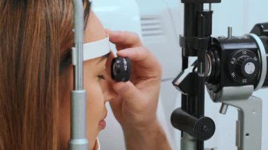 Göz doktorunda doktor ve güzel bir kadın göz testi makinesine bakıyor. Göz doktoruyum. Tıbbi yardım. Profesyonel göz doktoru muayene ediyor.