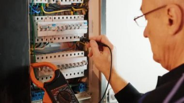 Elektrikçiler kontrol panelindeki elektrik akımını test ediyorlar. Elektrik mühendisi, kabine kontrolündeki voltaj ve elektrik hattının akımını ölçen bir testçi..