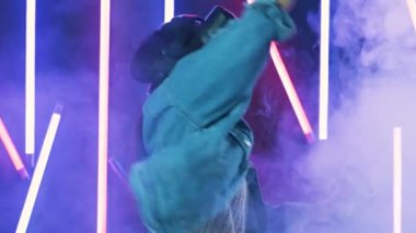 VR kulaklıkla oynayan ve gülümseyen genç bir kadın. Renkli duman arka planında sanal gerçeklik miğferi