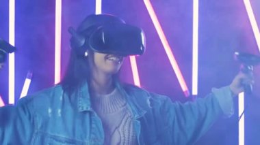 VR kulaklıkla dans eden genç bir kadın. Renkli duman arka planında sanal gerçeklik miğferi