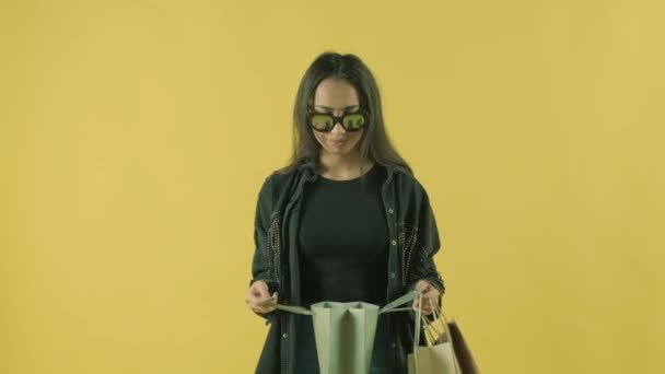 Sarı Arka Plandaki Alışveriş Torbasında Genç Güzel Görünüyor — Stok video