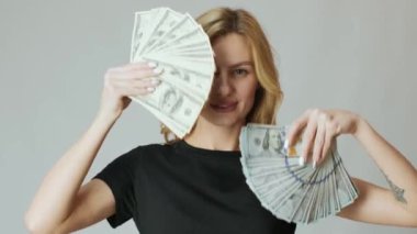 Elinde bir sürü para olan güzel bir kız ve beyaz arka planda alışveriş torbaları.