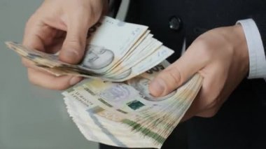 Erkeklerin elleri hızlıca banknotları sayar. İş adamı Ukraynalı Hryvna 'yı ele geçirdi.