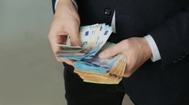 Erkeklerin elleri hızlıca banknotları sayar. İşadamı avrodan elde edilen banknotları sayıyor.