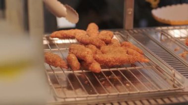 Aşçı maşaları tezgahtan tavuk külçelerini alır.