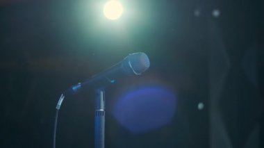 Rock konserinde sahne performansı sırasında mikrofonla şarkı söyleyen bir adam. Erkek rock yıldızını kapat. Renkli ışık arka planında müzik konseri ver.