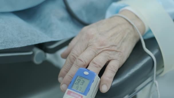 病院で手術中のモニタリングのために指にパルス酸素濃度計を持つ古い患者 — ストック動画