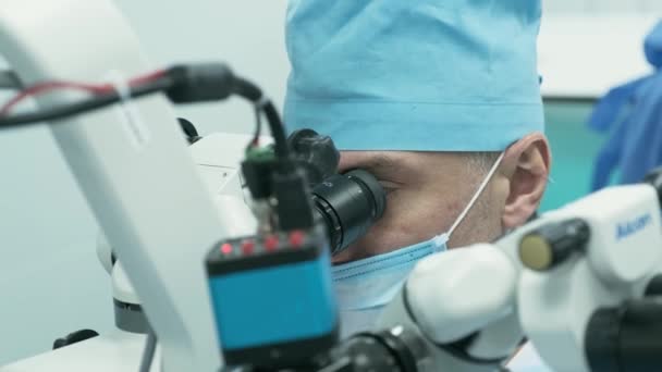 手術室で女性患者の目に顕微鏡を見る外科医 眼の手術中に顕微鏡を使用して医師 白内障の治療とダイオプターの補正 — ストック動画