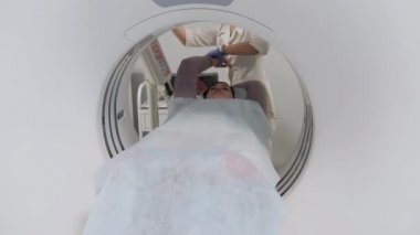 Doktor CT taramasından geçen bir kadın hasta hazırlıyor.