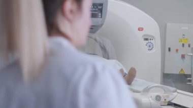 Tomografide ya da MRI tarayıcısında yatan kadın vücudunu görüntülerken kızılötesi ışınlar yakıyor ve kadın hasta çemberin içinden geçiyor, vinçle aşağıdan yukarıya, oda içi, aktif sahne..