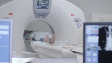 Tomografide ya da MRI tarayıcısında yatan kadın vücudunu görüntülerken kızılötesi ışınlar yakıyor ve kadın hasta çemberin içinden geçiyor, vinçle aşağıdan yukarıya, oda içi, aktif sahne..