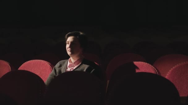 在黑暗的剧场里 女人坐在舒适的红色椅子上 — 图库视频影像