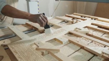 Ahşap işçilerinin dükkanında matkap ahşap bir desen kazıyor, bir marangoz fırça ile cips çıkarıyor..