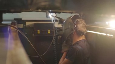 Araba servisi bir arabanın egzoz borusunu kaynaklayıp tamir ediyor. Kaldırılmış bir arabada kaynakçılık işi. Arkadan bak. Tamirci arabanın tabanını kaynaklıyor..